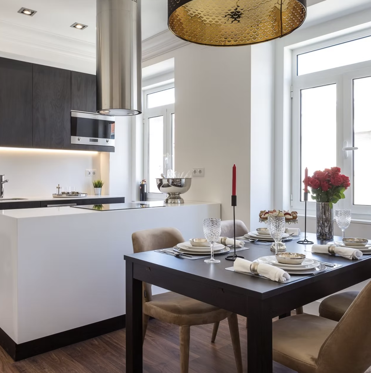 Cozinha e sala de jantar com candeeiro dourado e mesa posta